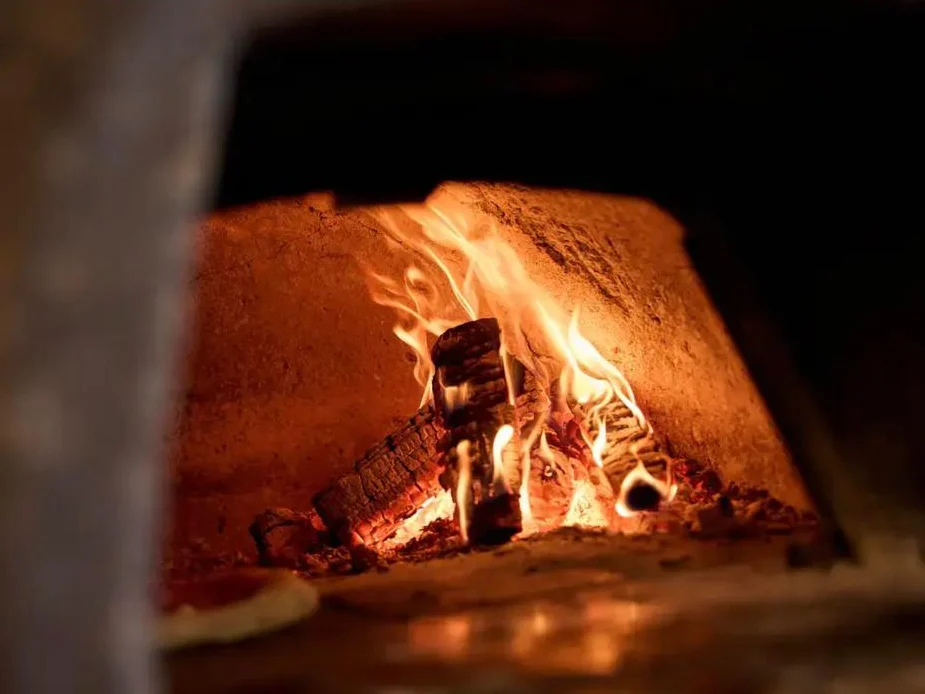 Wood-fired pizza oven burning in a UK restaurant kitchen